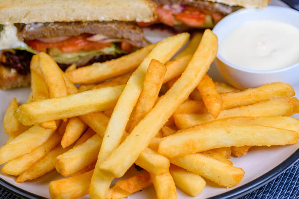 Frites épaisses servies avec sandwich et sauce blanche