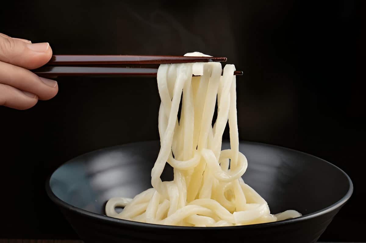 Nouilles udon maison prêtes à cuire Nouilles udon fraîches faites maison sur rouleau en bois