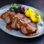 Sauerbraten en tranches servi avec boulettes de pommes de terre et chou rouge