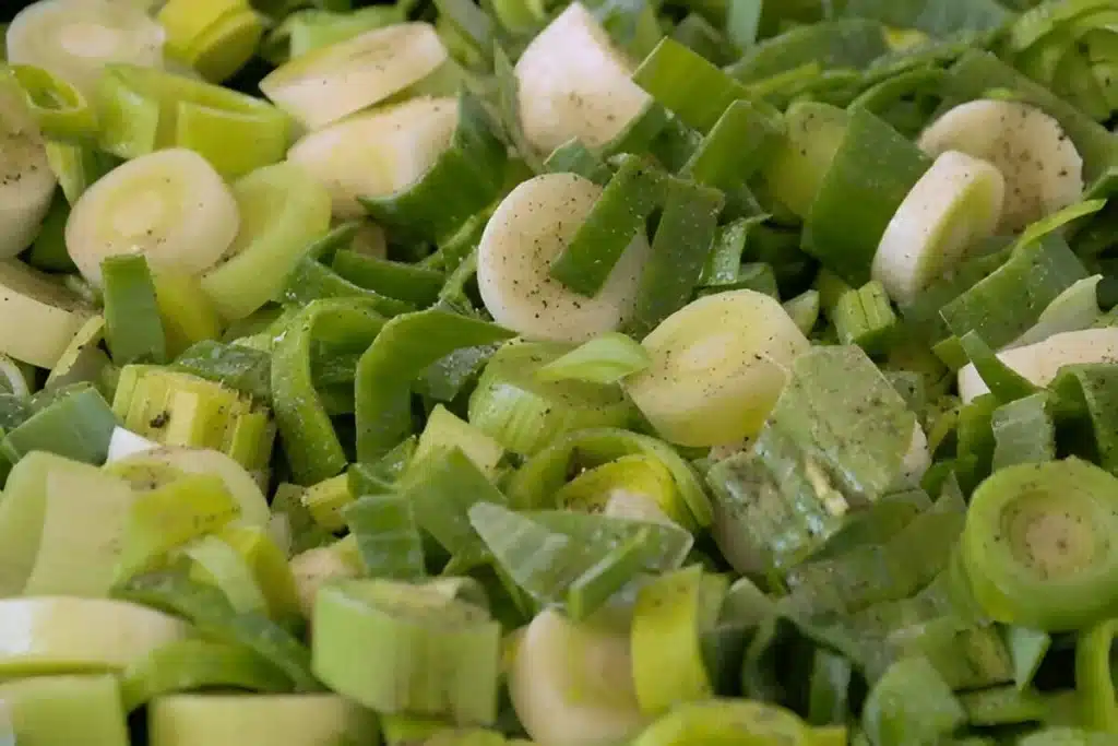 Poireaux frais émincés et assaisonnés avant cuisson.