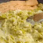 Saumon accompagné d'une fondue de poireaux à la crème dans une poêle.