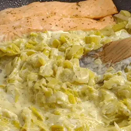 Saumon accompagné d'une fondue de poireaux à la crème dans une poêle.