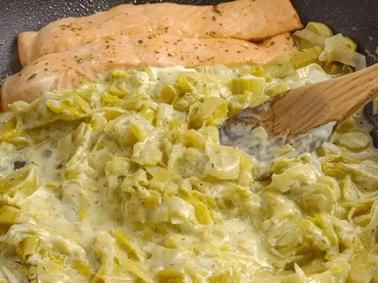 Saumon accompagné d'une fondue de poireaux à la crème dans une poêle.