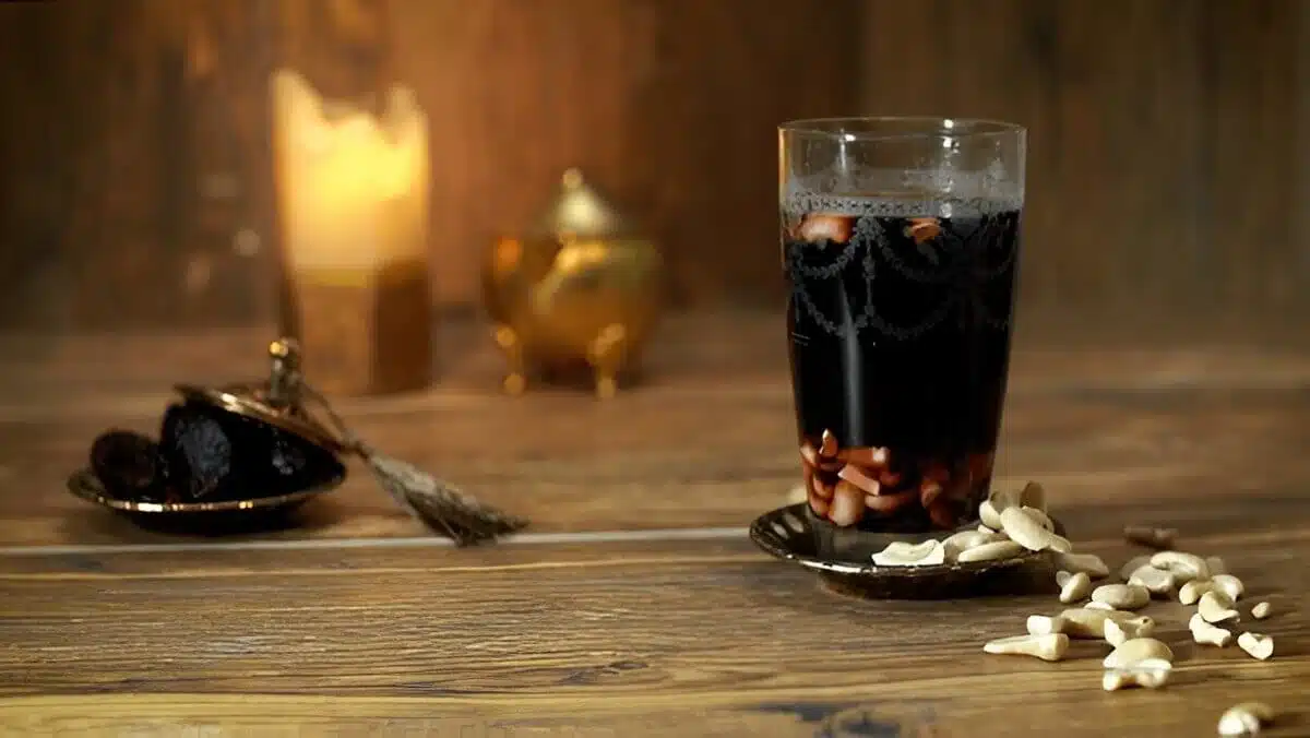Verre de Jallab posé sur une table en bois avec des noix de cajou et une ambiance chaleureuse.