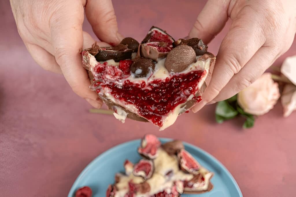 Morceau d’œuf en chocolat maison avec une couche de confiture de framboise visible.