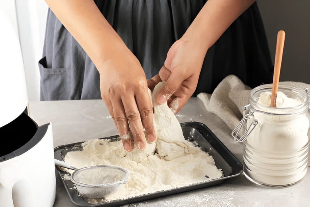 Femme en train de fariner du poulet sur un plan de travail propre