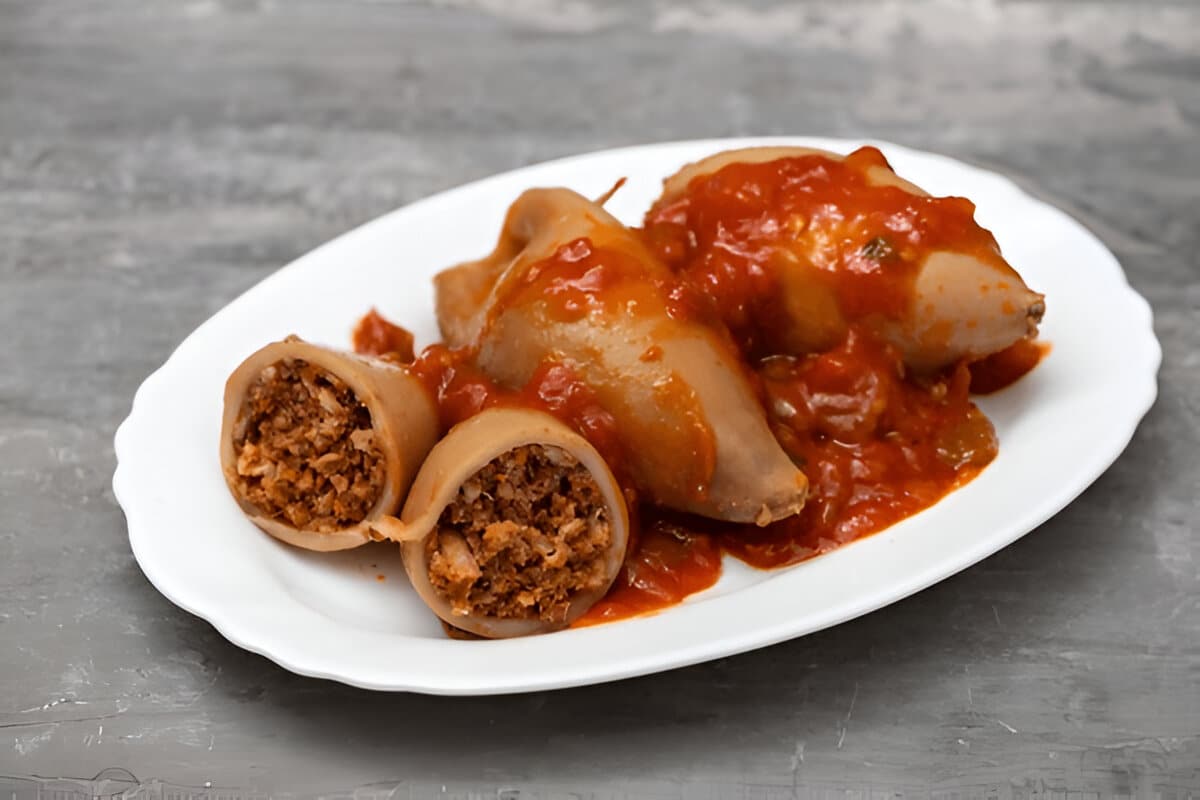 Encornets crus farcis, disposés dans une assiette blanche.